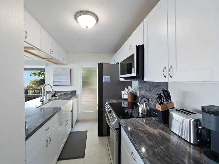 Galley kitchen with granite counters and stainless appliances