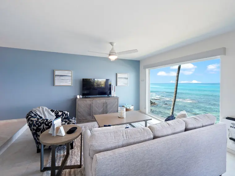 Living room with TV, sectional, and ocean through sliding doors